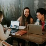 Employees laughing while working around a table with laptops