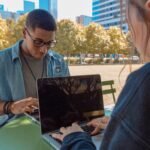 Two people working on their laptop on a table outside