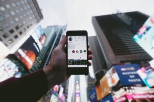 Instagram page on smartphone in hand with with Time Square, NY in background
